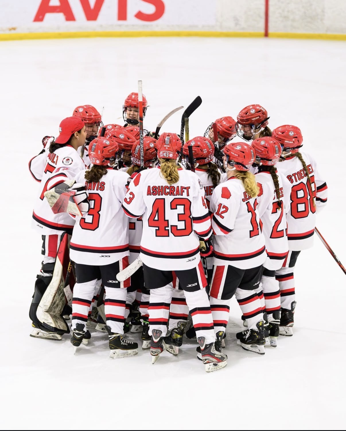 An image of a hockey team huddled together on the ice celebrating a win.